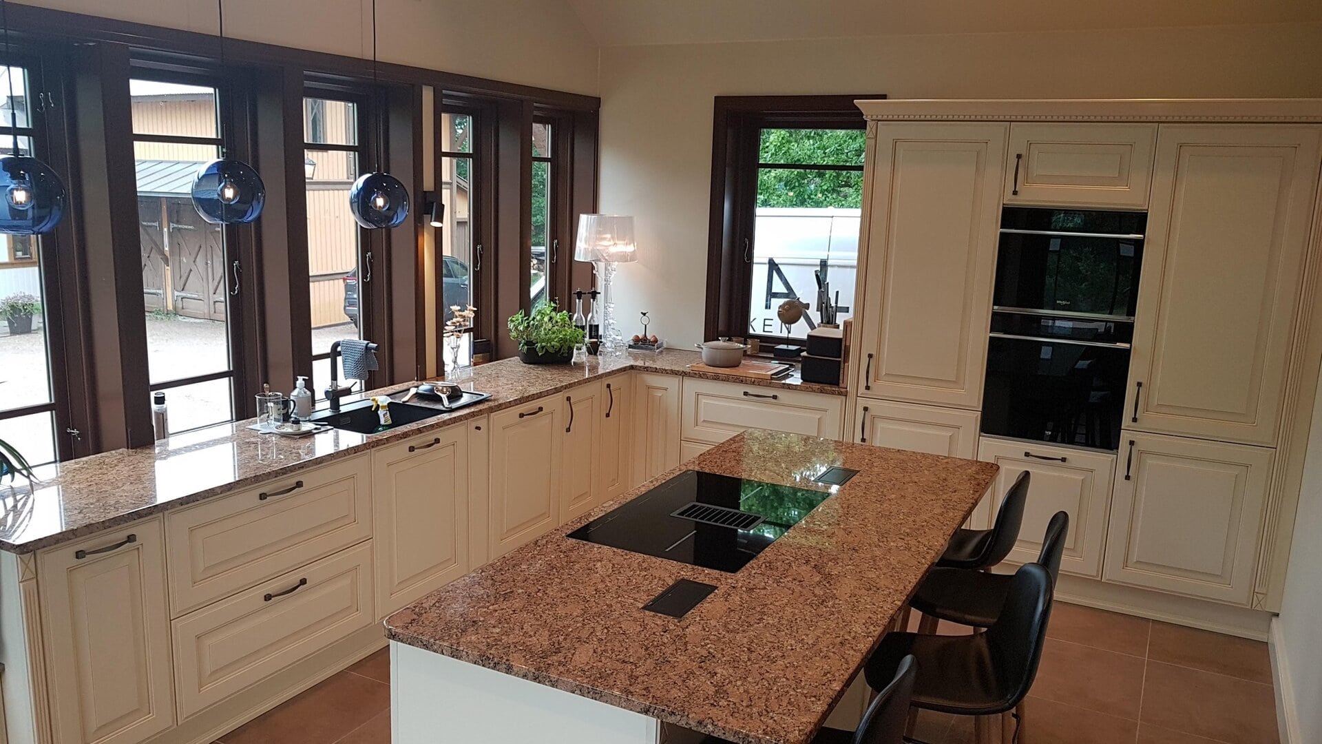 Lys kjøkken med hvite skandinaviske skap, granittbenkeplate og store vinduer, moderne design, funksjonelt kjøkken, naturlig lys, hjemmekoselig atmosfære, inspirerende kjøkkenidéer.