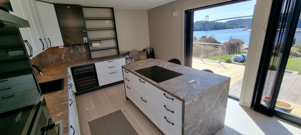 Moderne kjøkken med fantastisk utsikt over fjorden og bygd, perfekt for komfort og stil i din nye nettside.