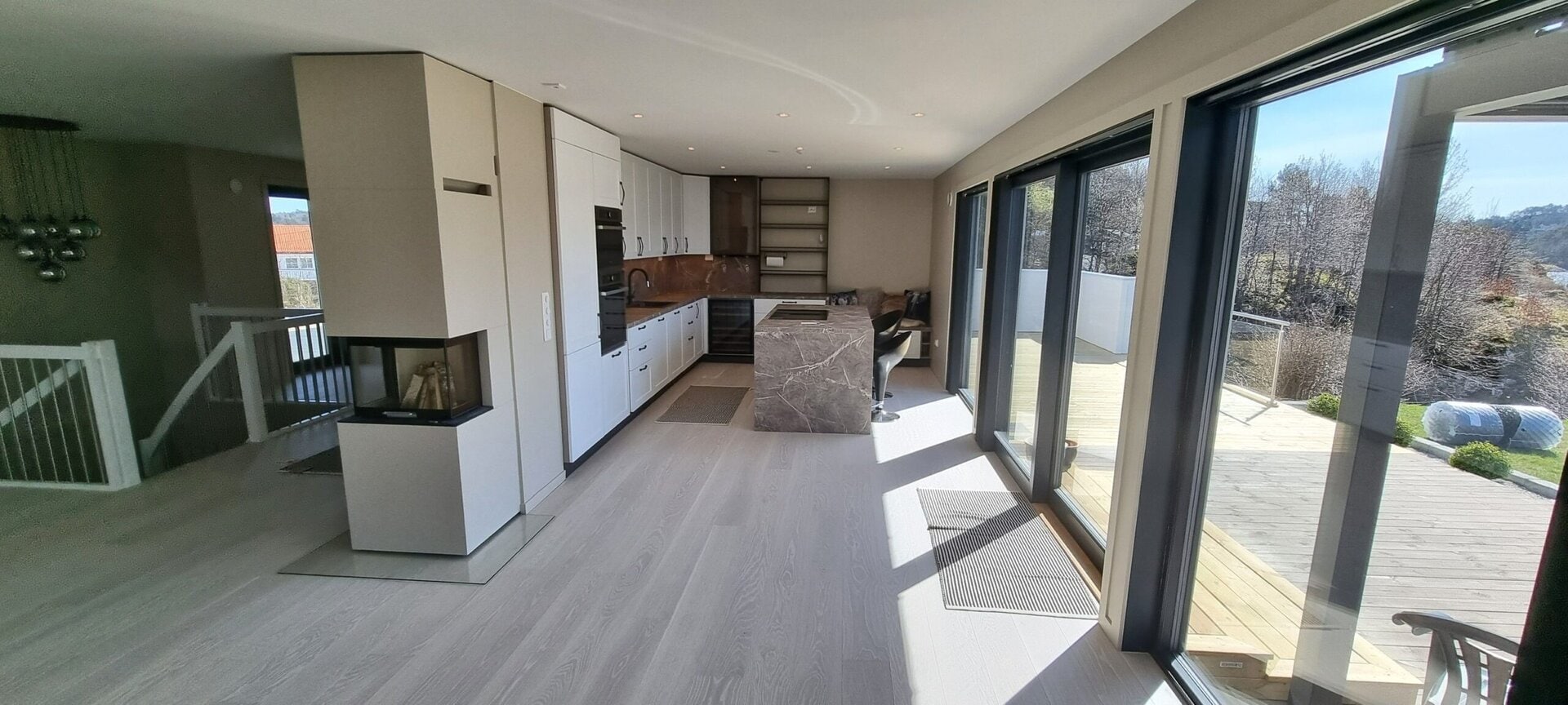 Moderne kjøkken med store glassdører til uteplassen, naturlig lys og elegant design, perfekt for hjemmekos og samtaler.